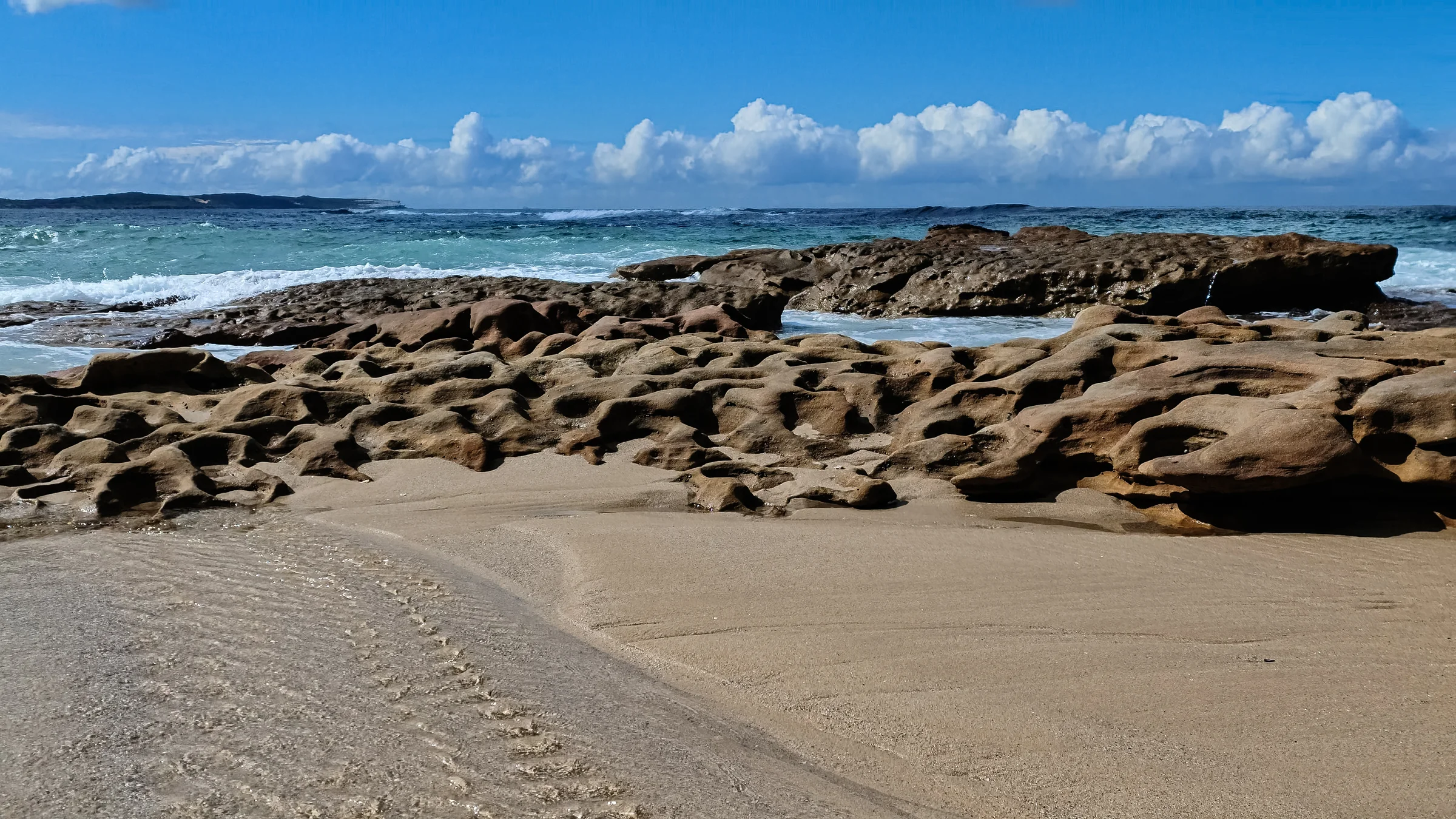 Sand and weathered sandstone beside the ocean at Blackwoods Beach