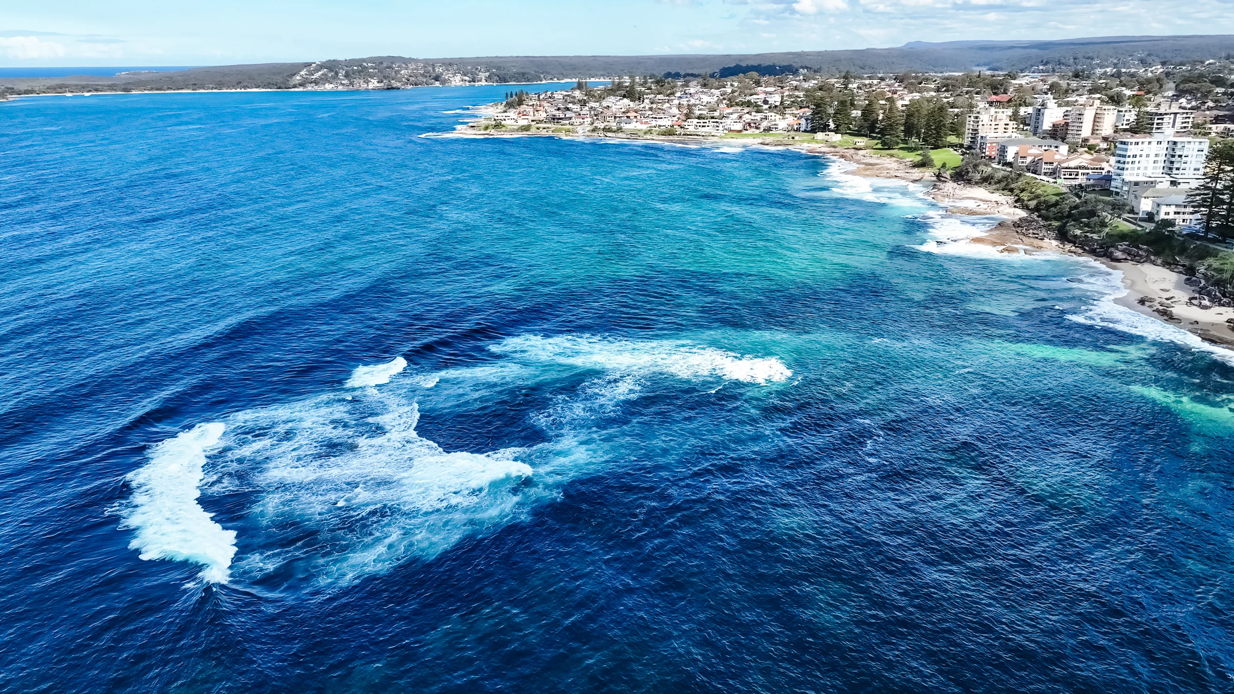 Aerial view of Shark Island reef with breaking waves and the Cronulla coastline beyond