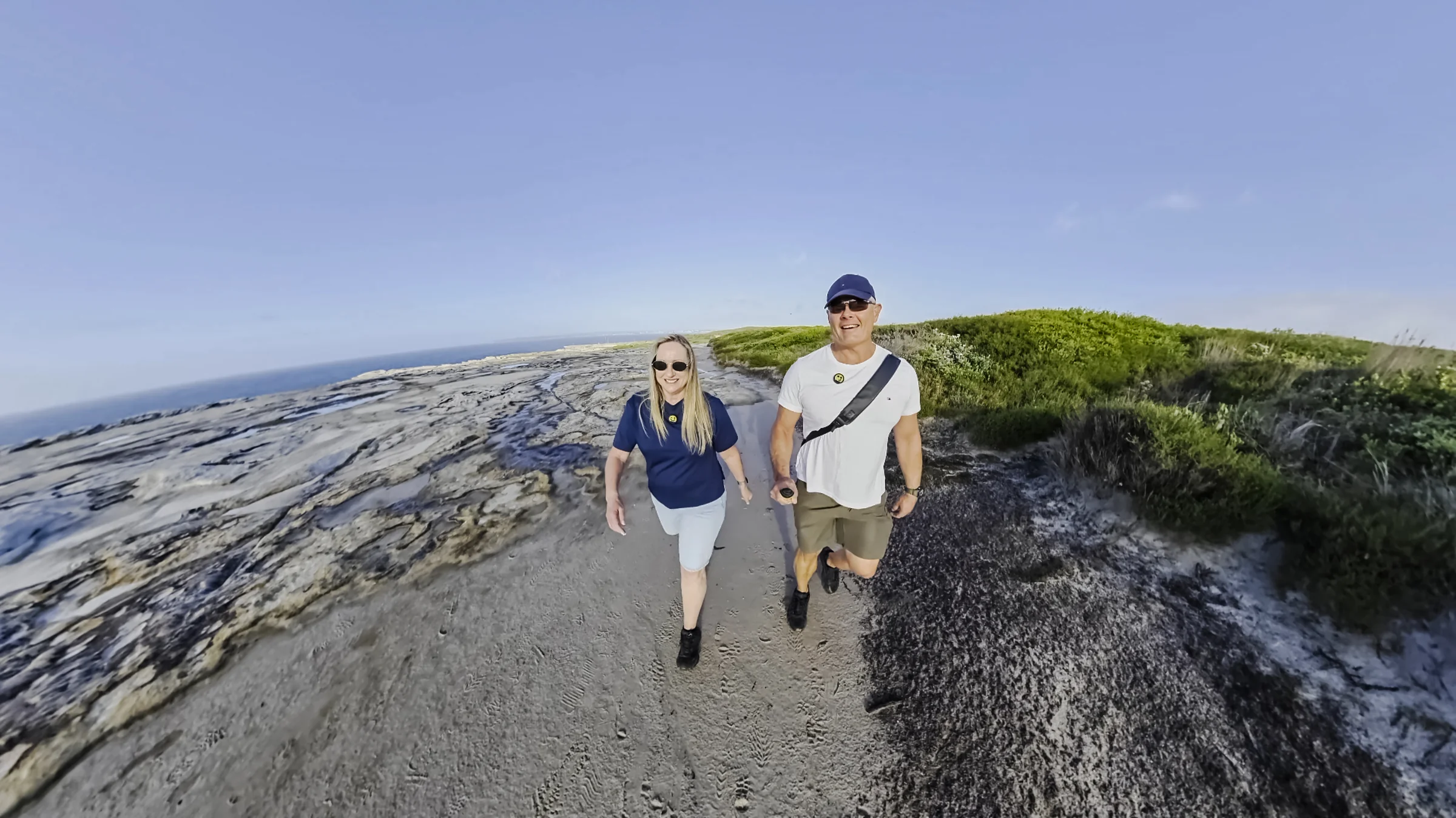 Rob and Sue walking on the sandstone beside the ocean