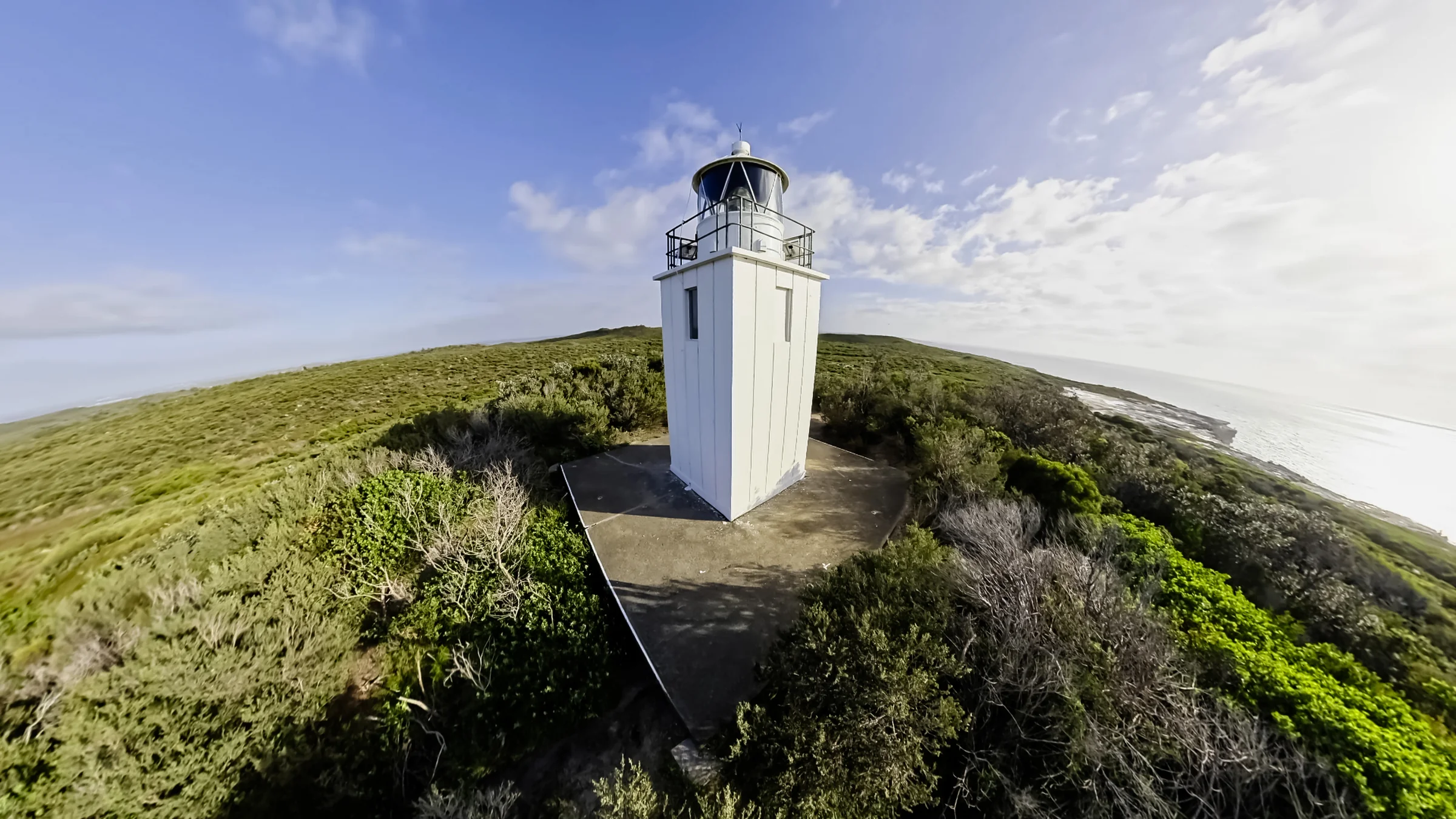 Cape Baily Lighthouse surrounded by green heath with ocean beyond