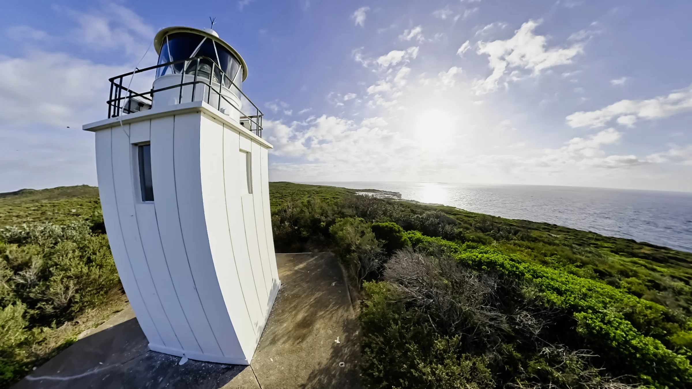 Close view of the white lighthouse tower and lantern against the sky