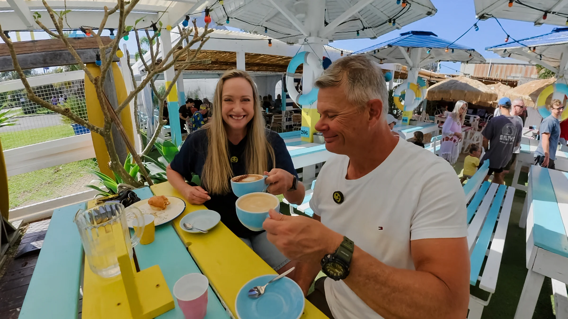 Rob and Sue with coffee cups at an outdoor table at Cook at Kurnell