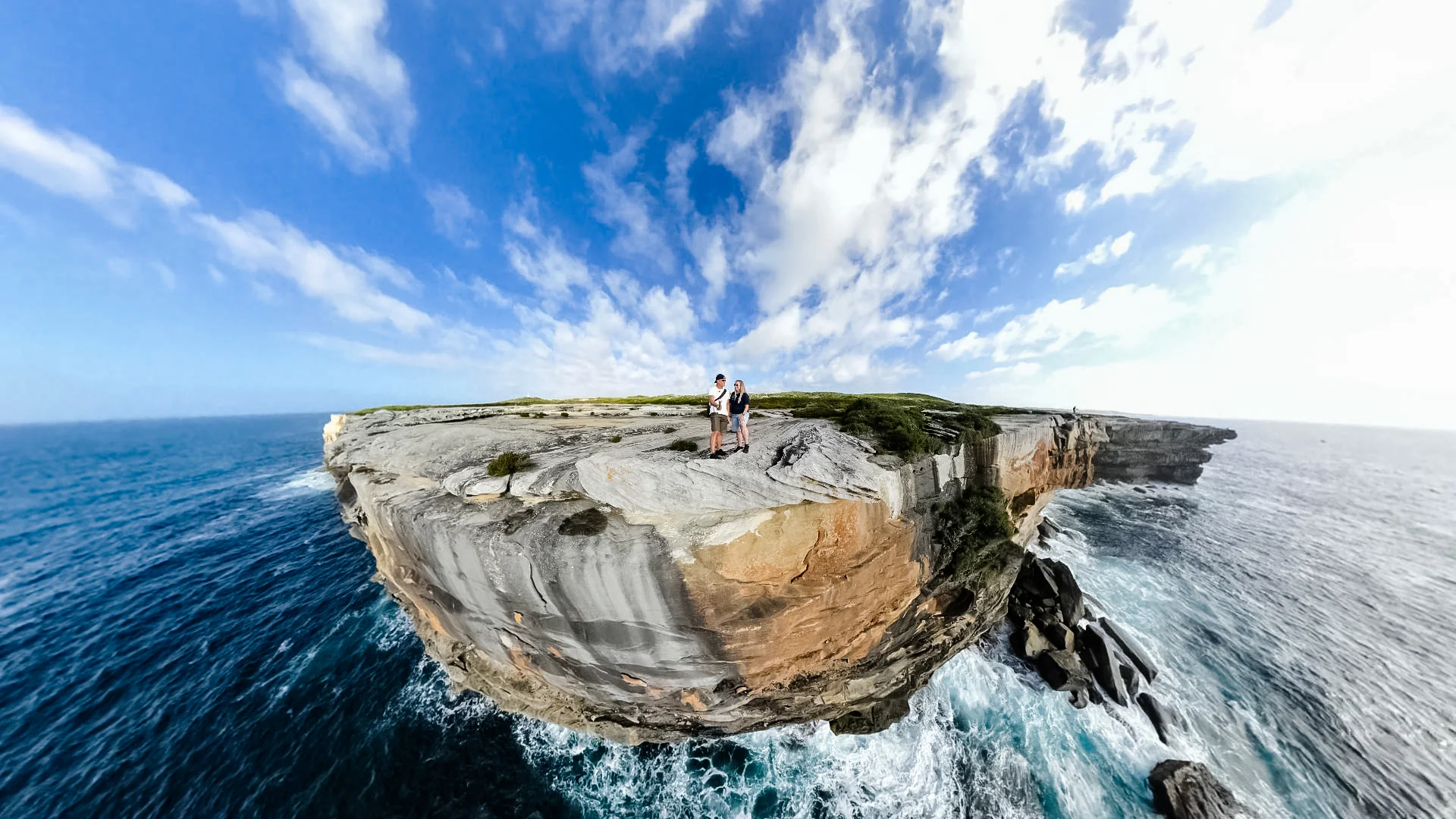 Rob and Sue on a sandstone headland surrounded by blue ocean and breaking surf