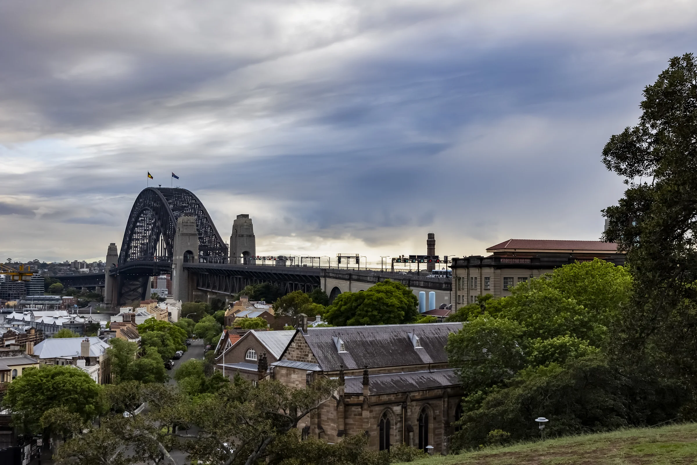 Sydney Harbour Bridge beyond the park and rooftops at Observatory Hill