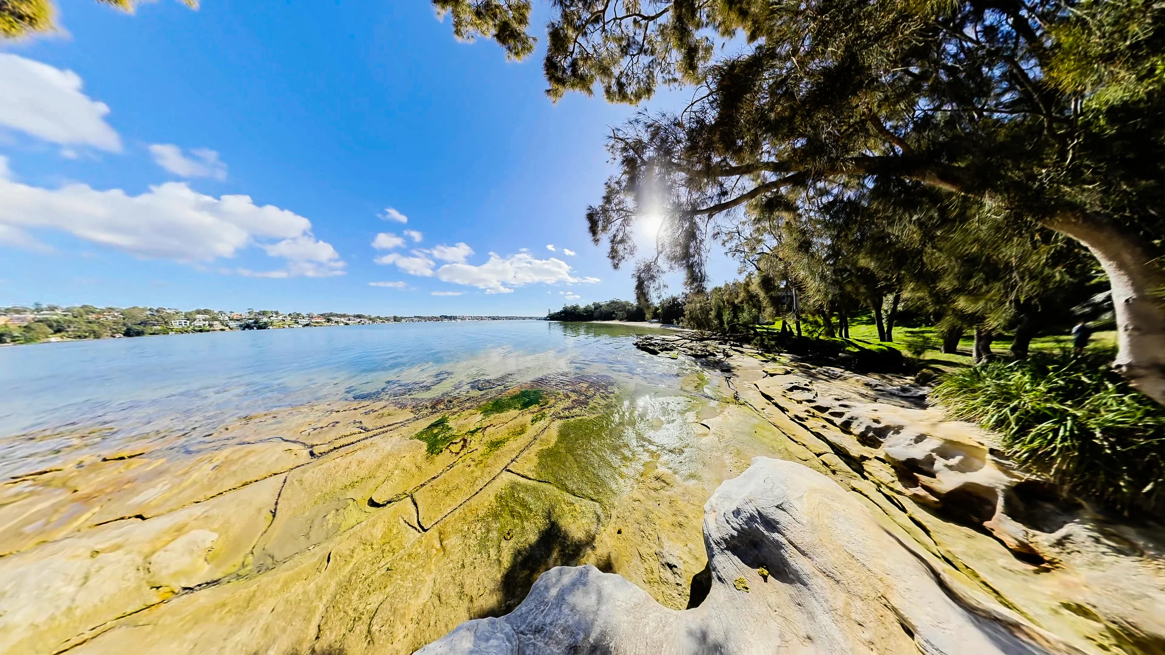 Sunlit rock shelves beside the water and shady trees at Darook Park