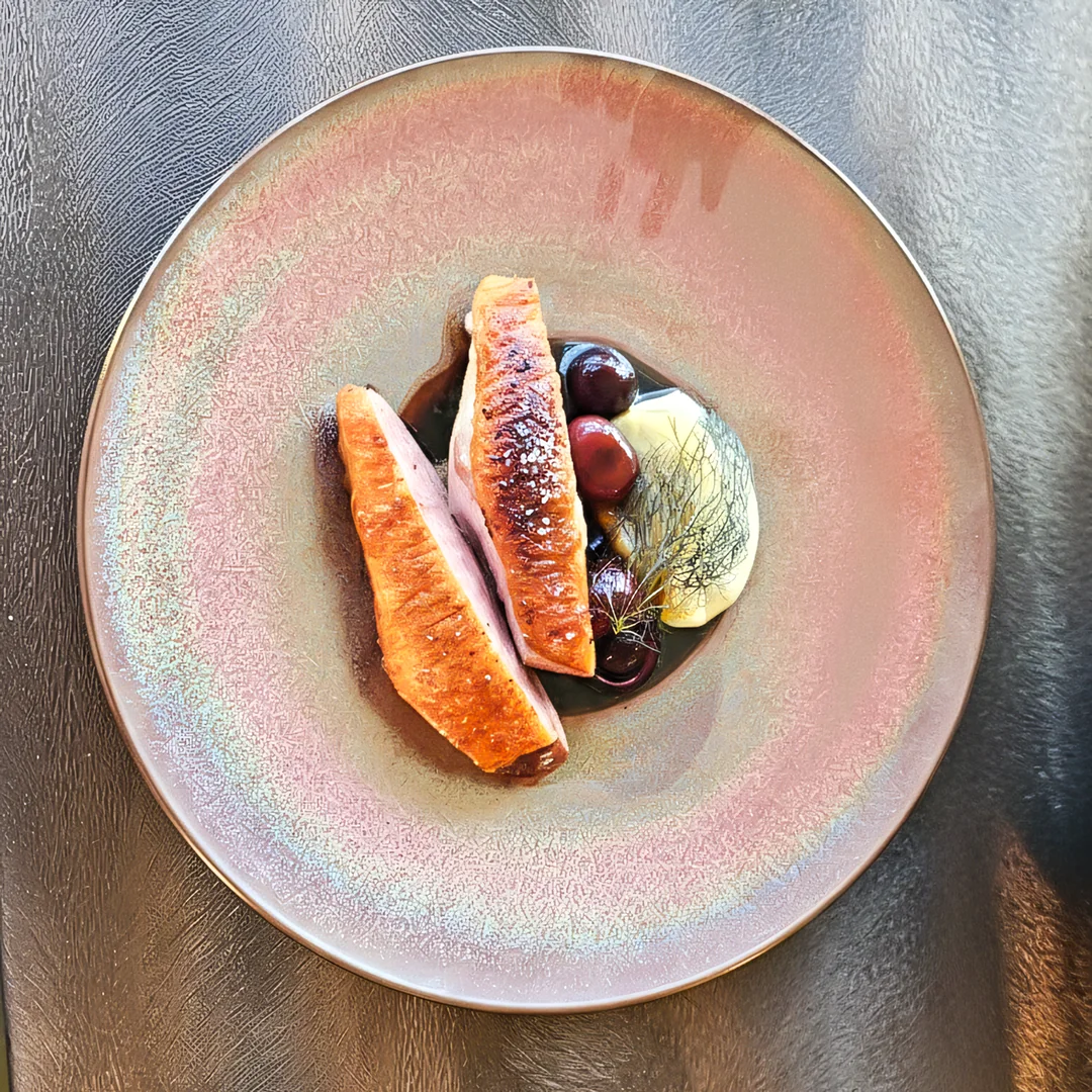 Sliced meat with sauce on a pink plate