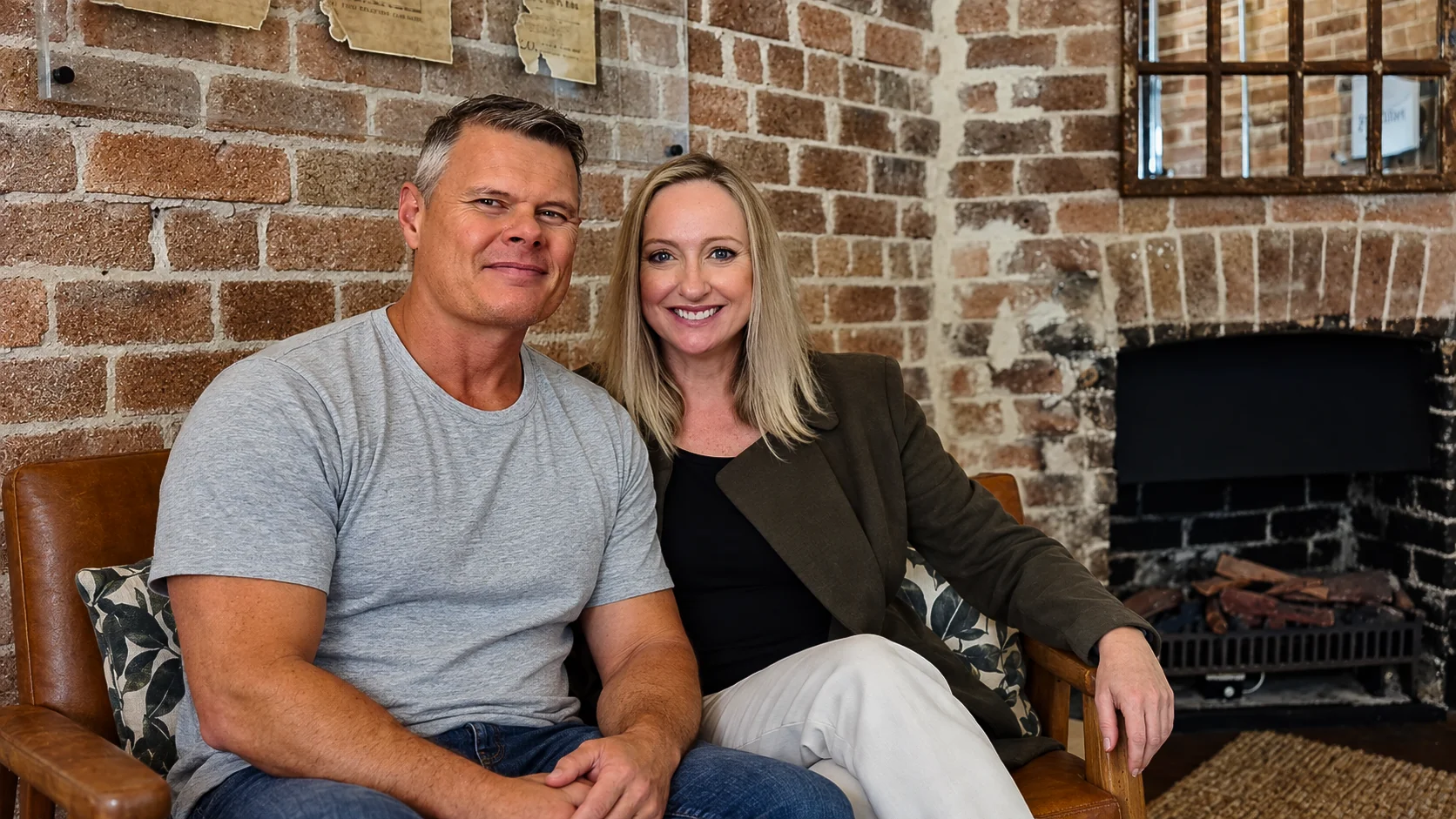 Rob and Sue seated beside a brick fireplace