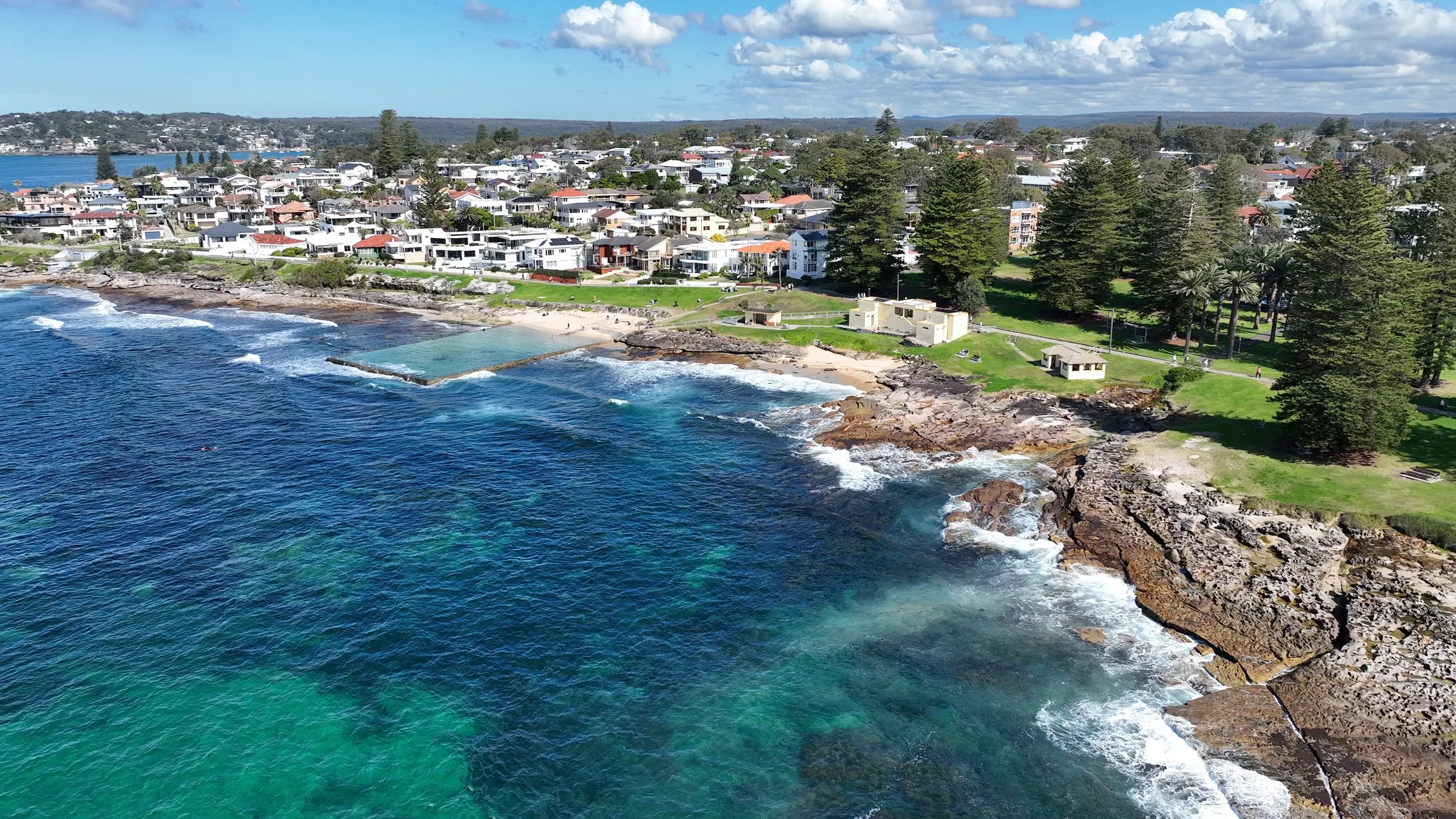 Wide aerial view along the Cronulla coast towards Shelly Beach and its park