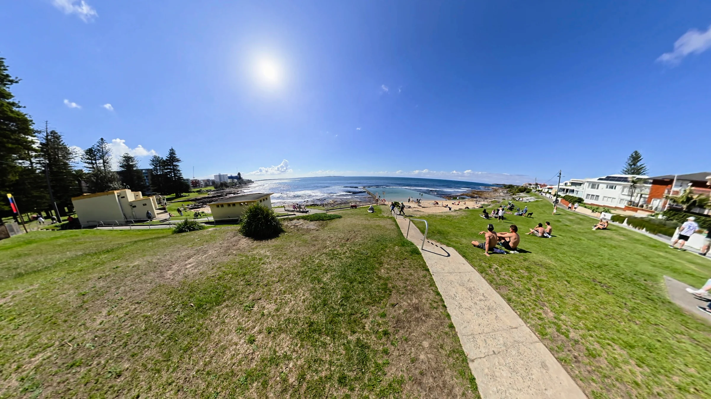 Wide view down the grassy slope towards Shelly Beach pool and the ocean