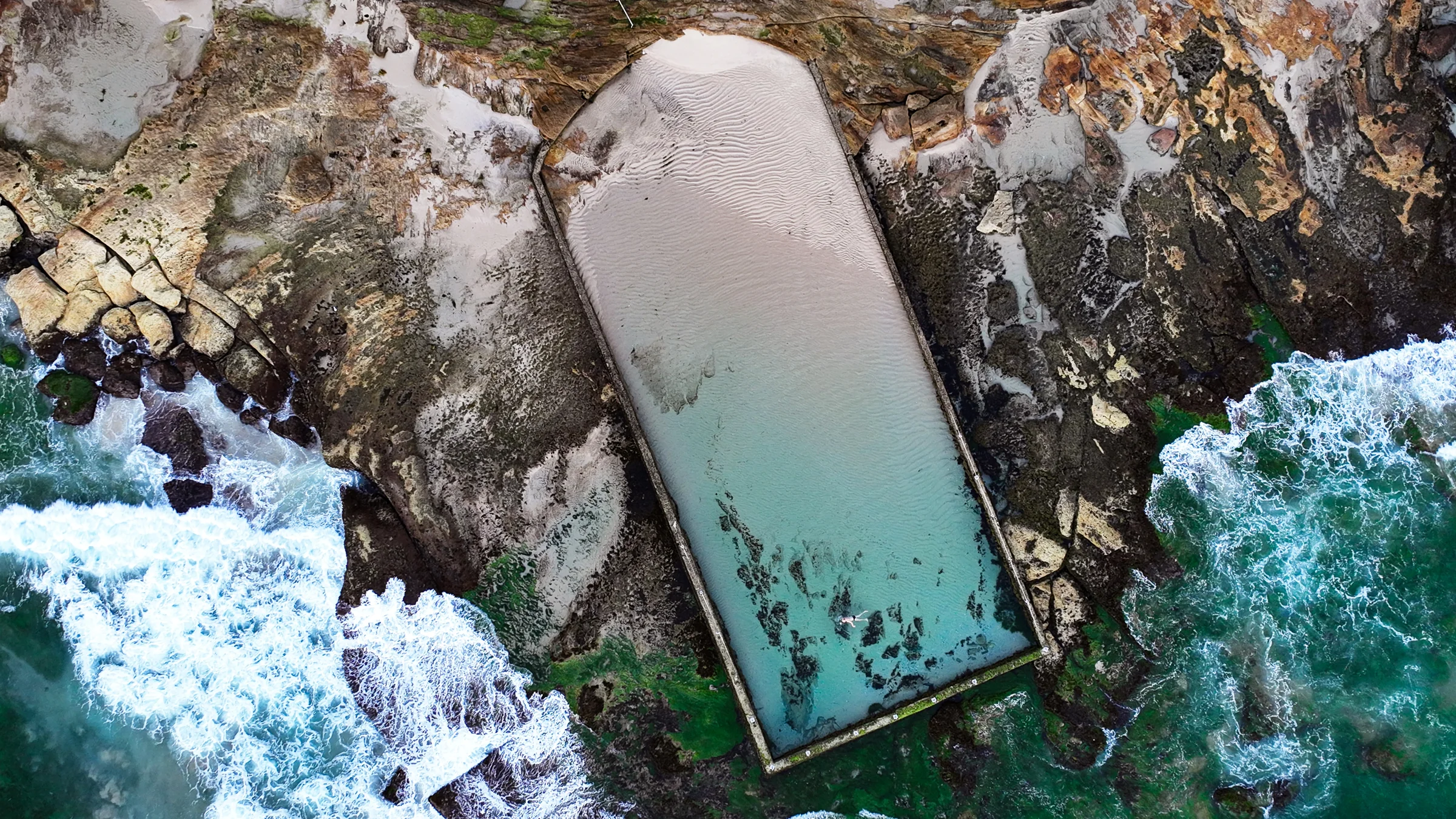 The smaller Cronulla ocean pool with sand and shallow water viewed from above