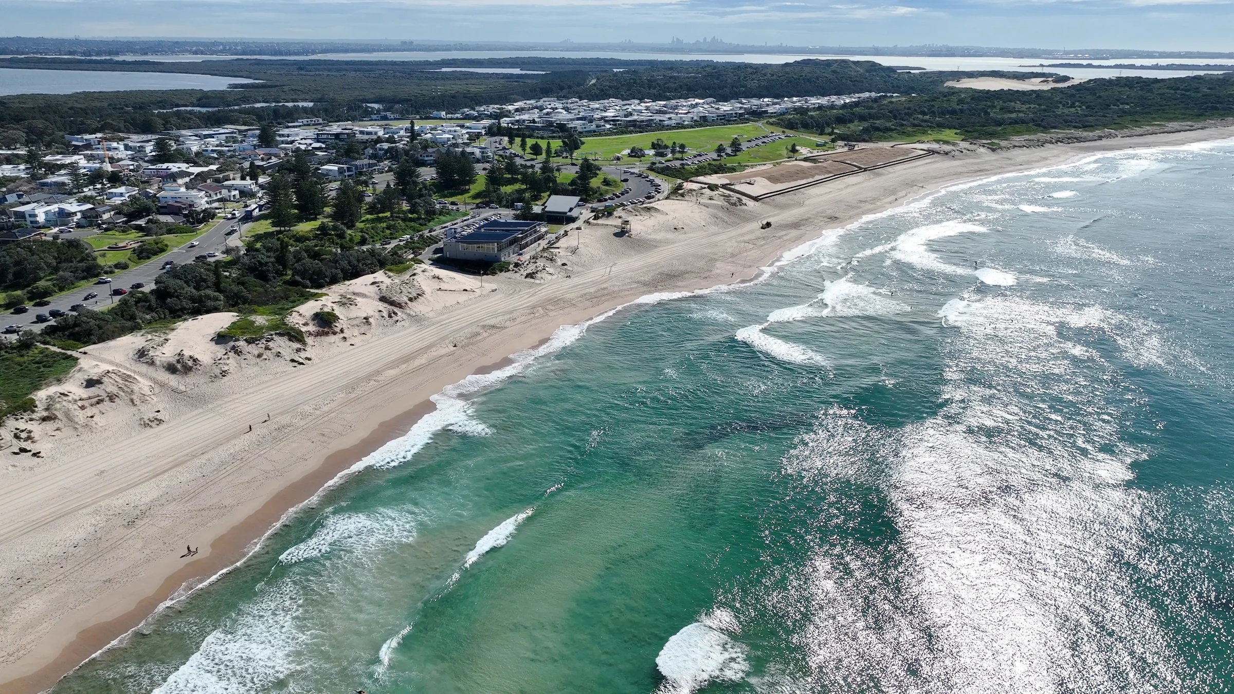 Aerial view of Wanda Beach, its surf club, sand dunes and coastline stretching north