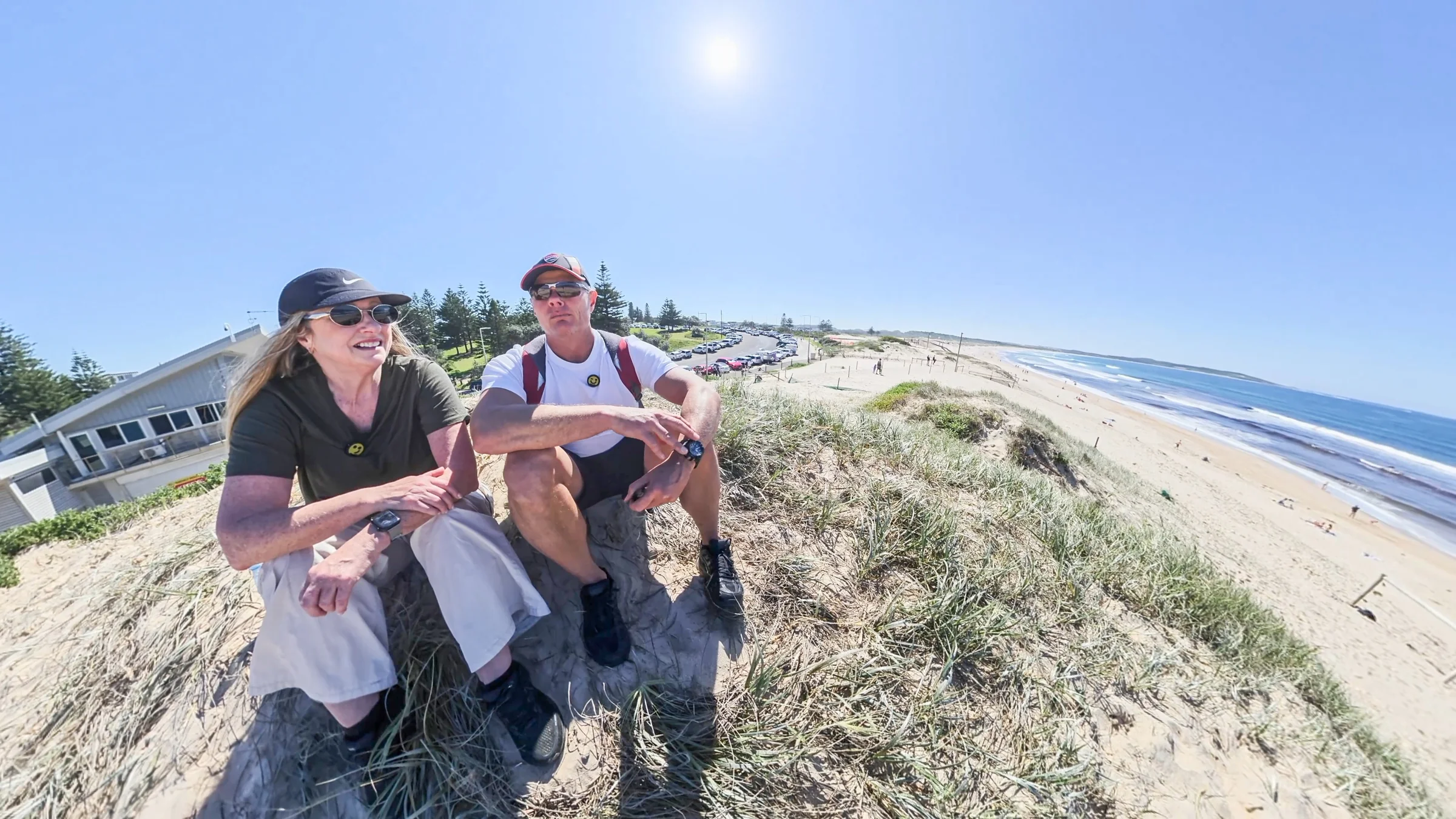 Rob and Sue sitting above Wanda Beach with the surf club and sand behind them