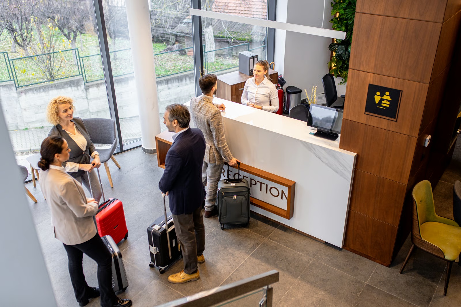 Hotel guests with suitcases checking in at a staffed reception counter with a Reception sign
